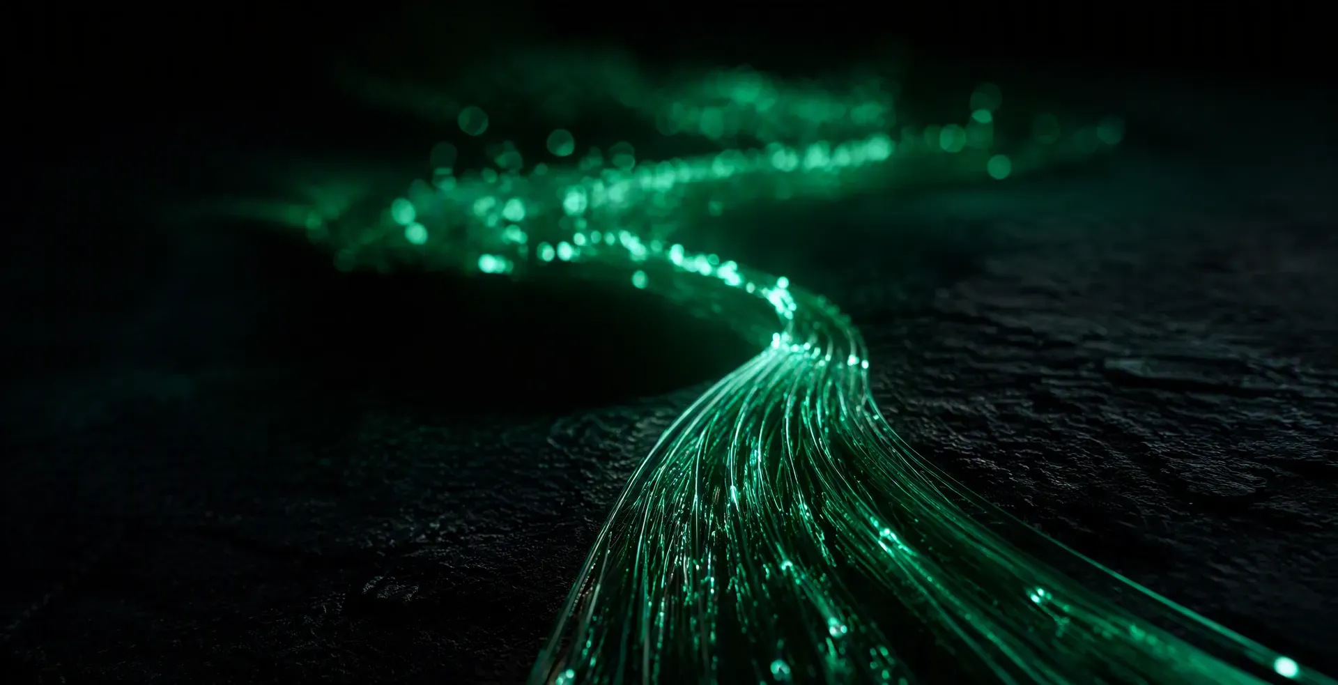 Fiber optic strands streaming emerald light across black stone like a river of data — Veles Labs custom software